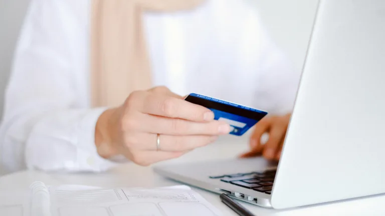 A woman holding her credit card to pay for an online purchase